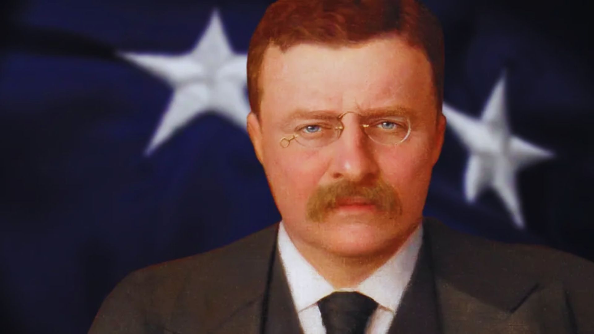 A man with a mustache and glasses stands in front of an American flag, showcasing patriotism and national pride.