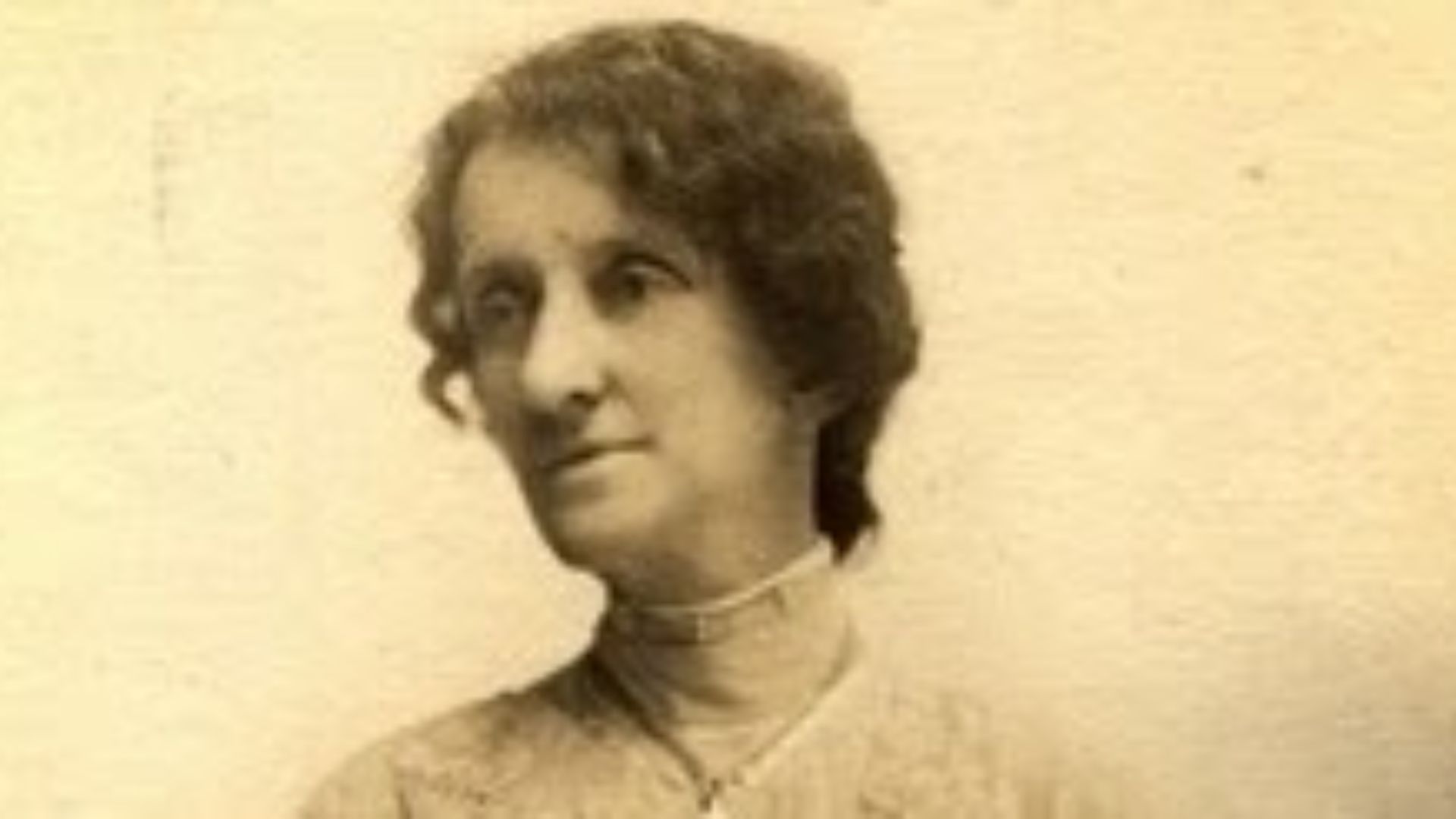 Vintage photograph of a woman wearing a long dress, standing outdoors.