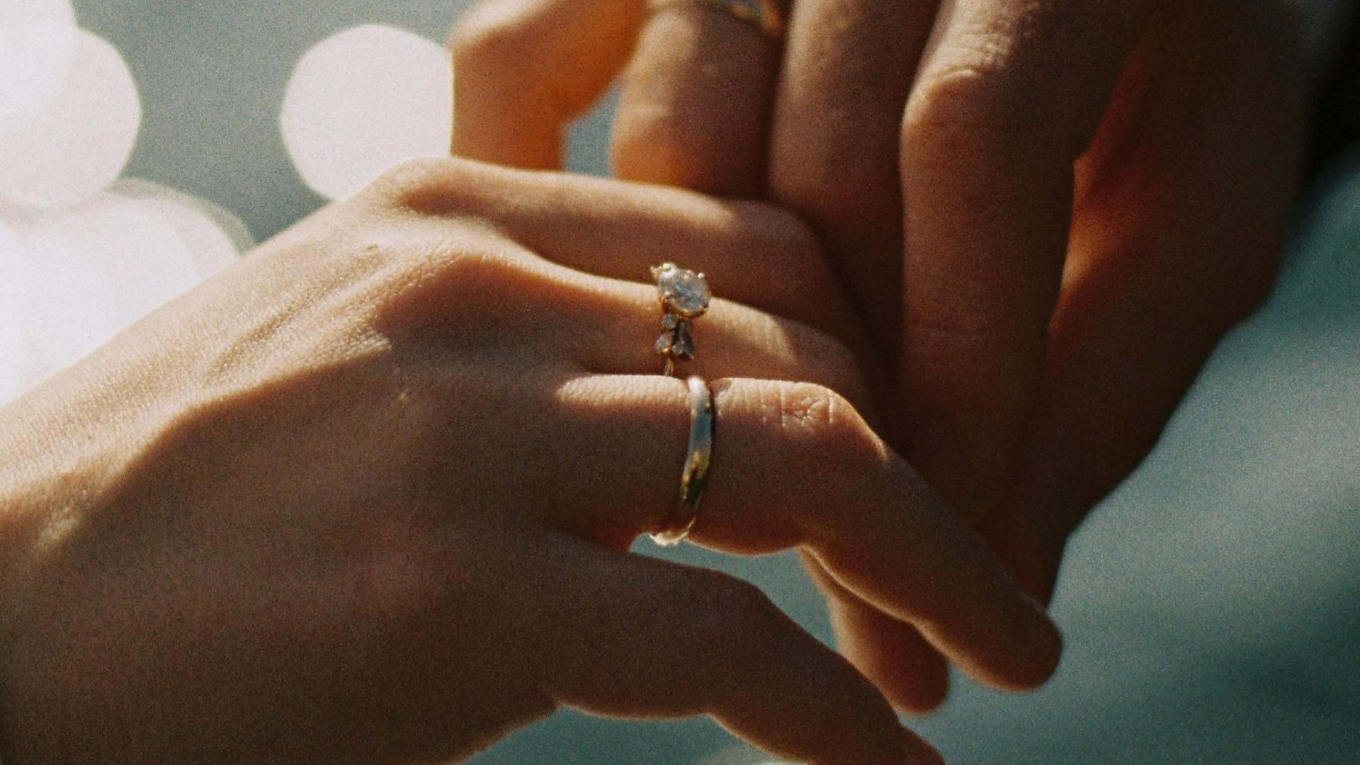 Newlywed couple holding hands, wedding rings visible.