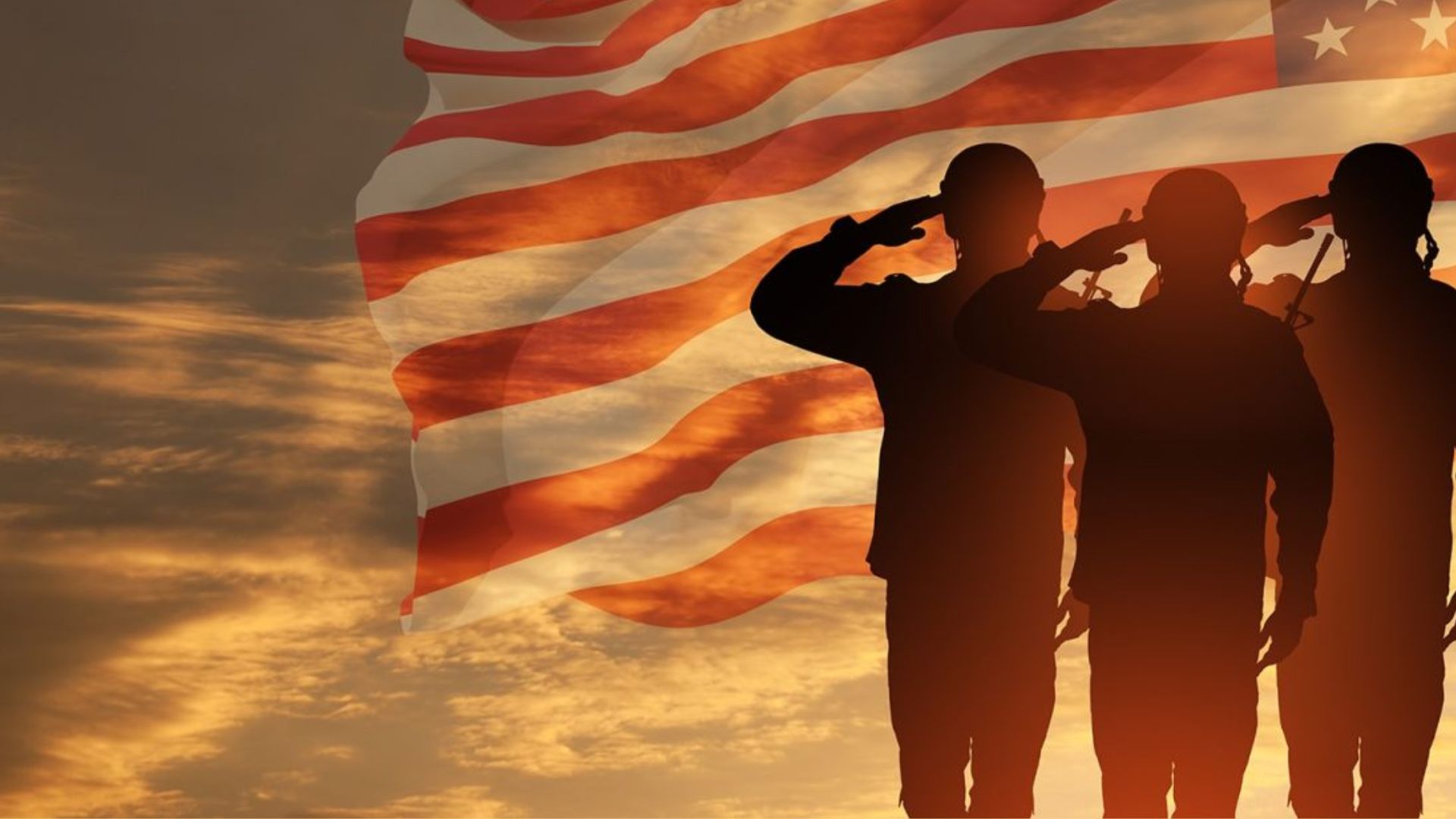 Three soldiers stand at attention, saluting the American flag waving in the breeze.