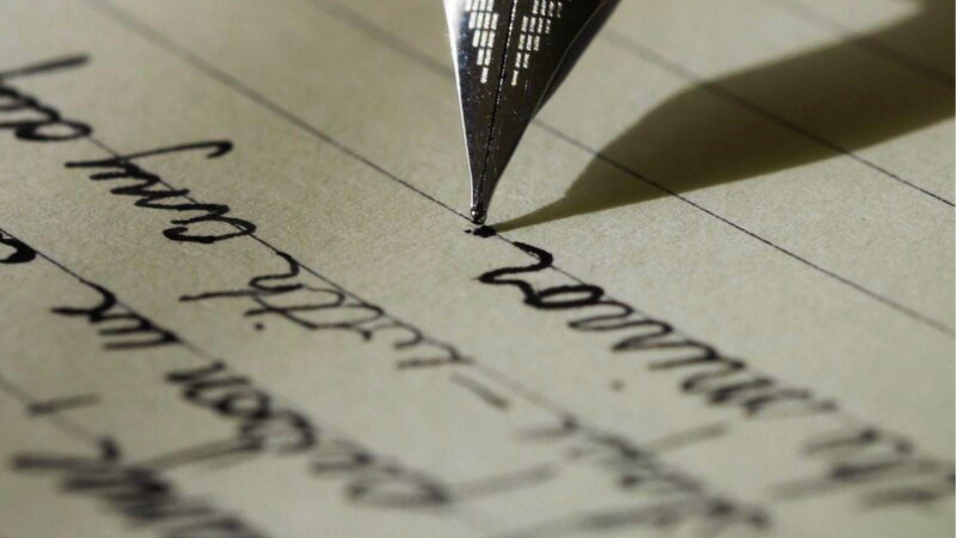 Close-up of fountain pen nib writing cursive on lined paper, showing the steady rhythmic flow of poetic meter and cadence.