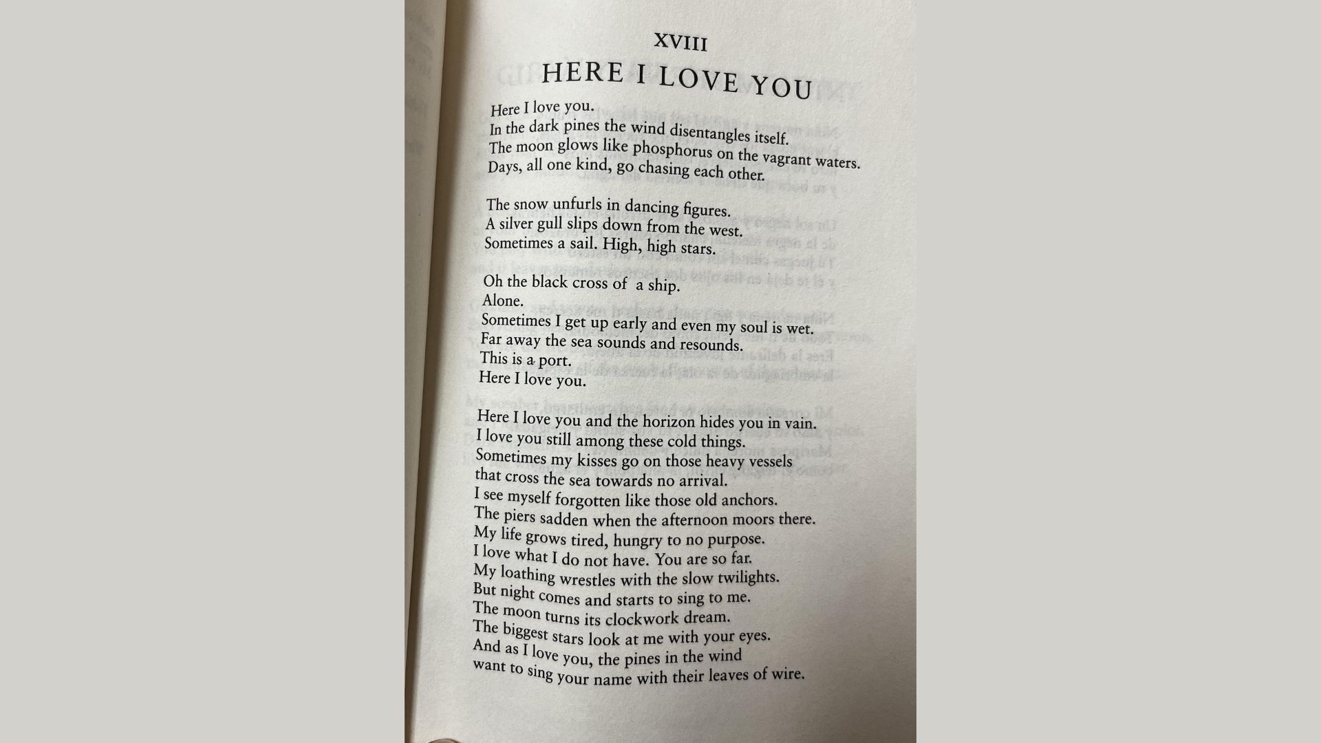 "Open book showing Pablo Neruda poem XVIII 'HERE I LOVE YOU' printed in black text."
