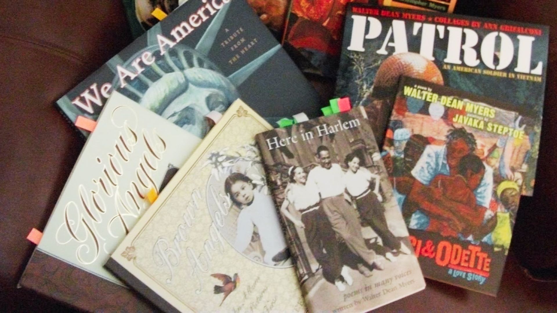 A collection of books by Walter Dean Myers spread on a surface, including poetry titles like Here in Harlem, Brown Angels, and Patrol.