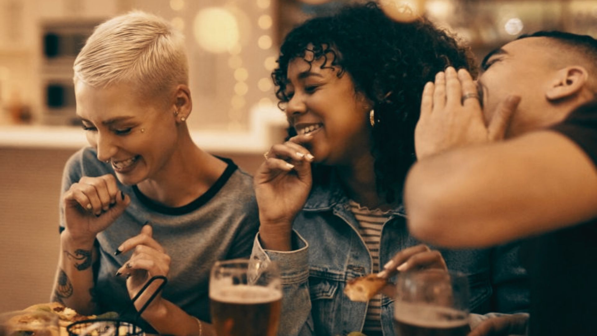 Three friends smiling while drinking.