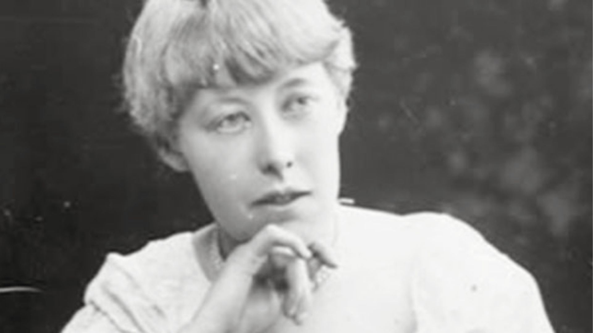 Vintage black-and-white portrait of Katharine Tynan, hands clasped thoughtfully under her chin.
