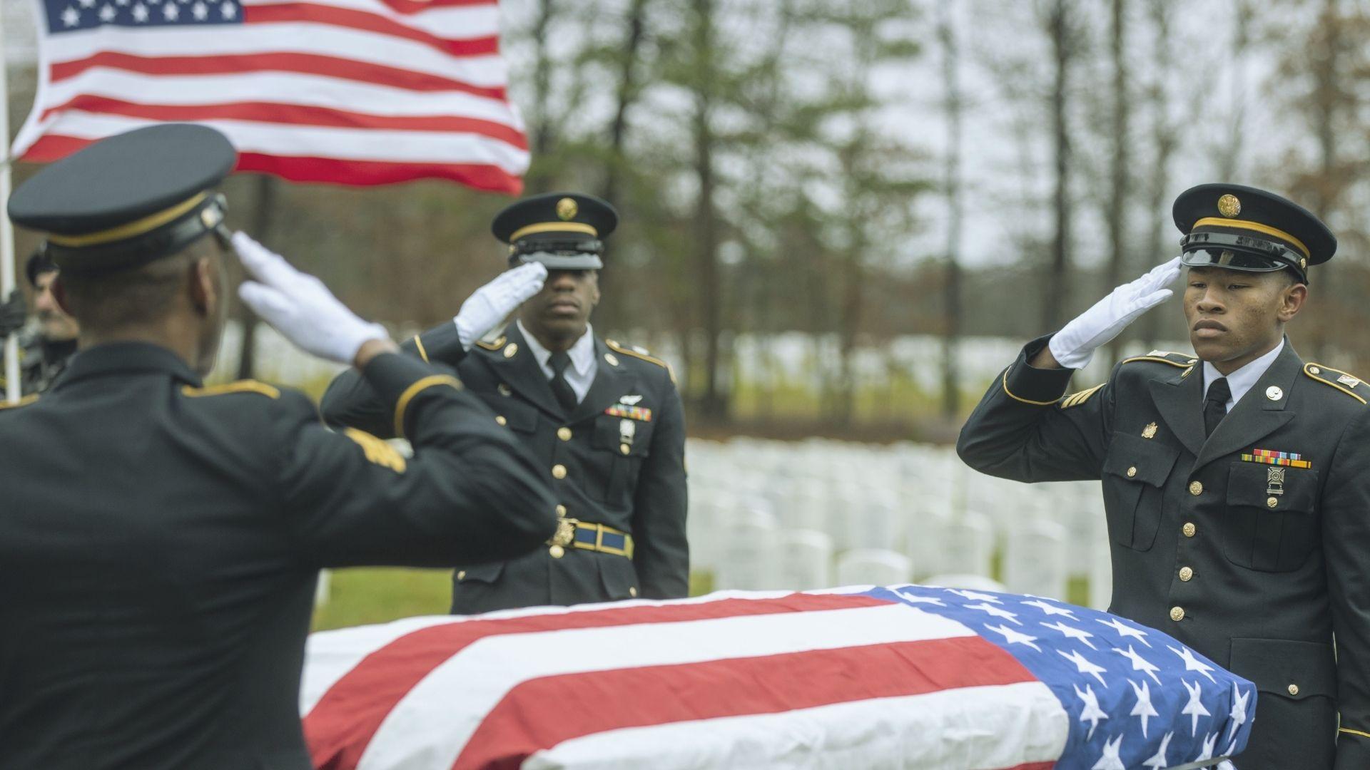 U.S. Army soldiers saluting a flag-draped casket at a military funeral