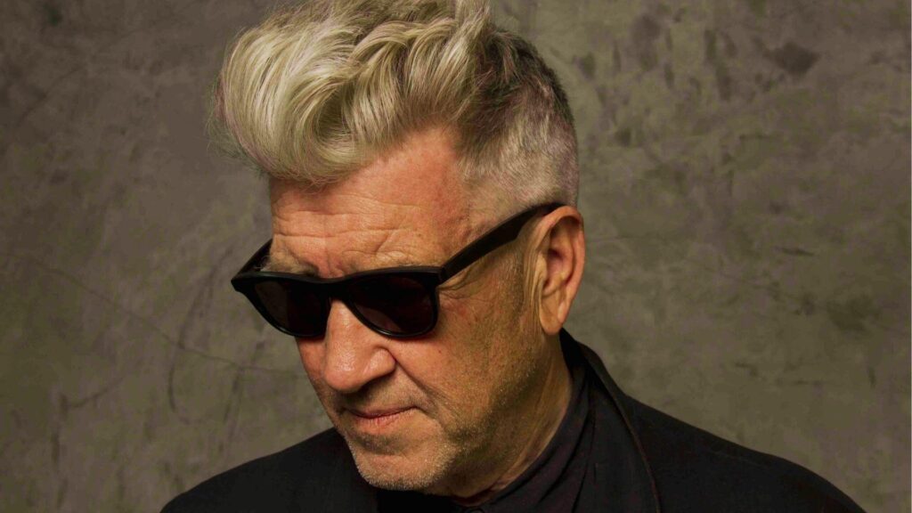 David Lynch wearing sunglasses with his signature swept-back hairstyle