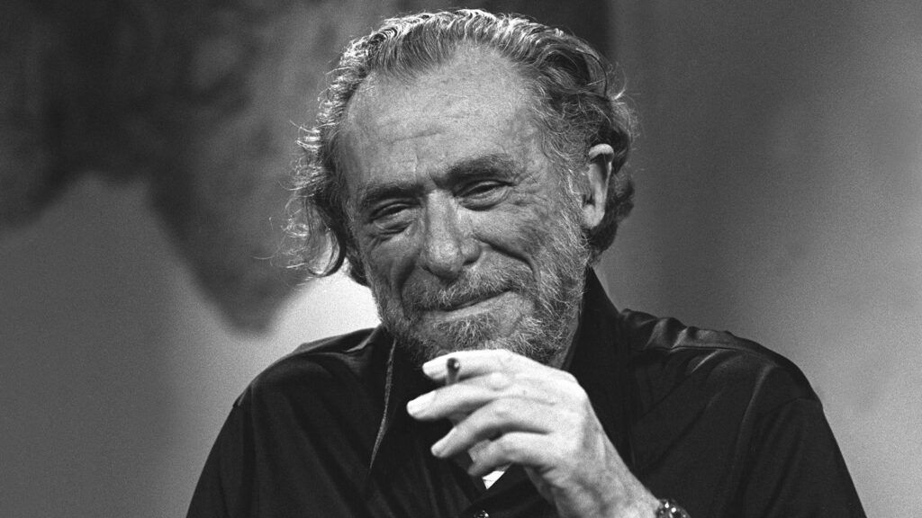 A man holding a cigarette in the black and white setup File name: charles-bukowski-portrait-image