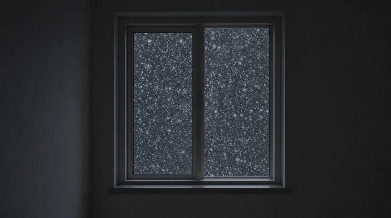 Dark interior with bright window showing heavy snowfall outside at nightFile name: dark-window-heavy-snowfall-night
