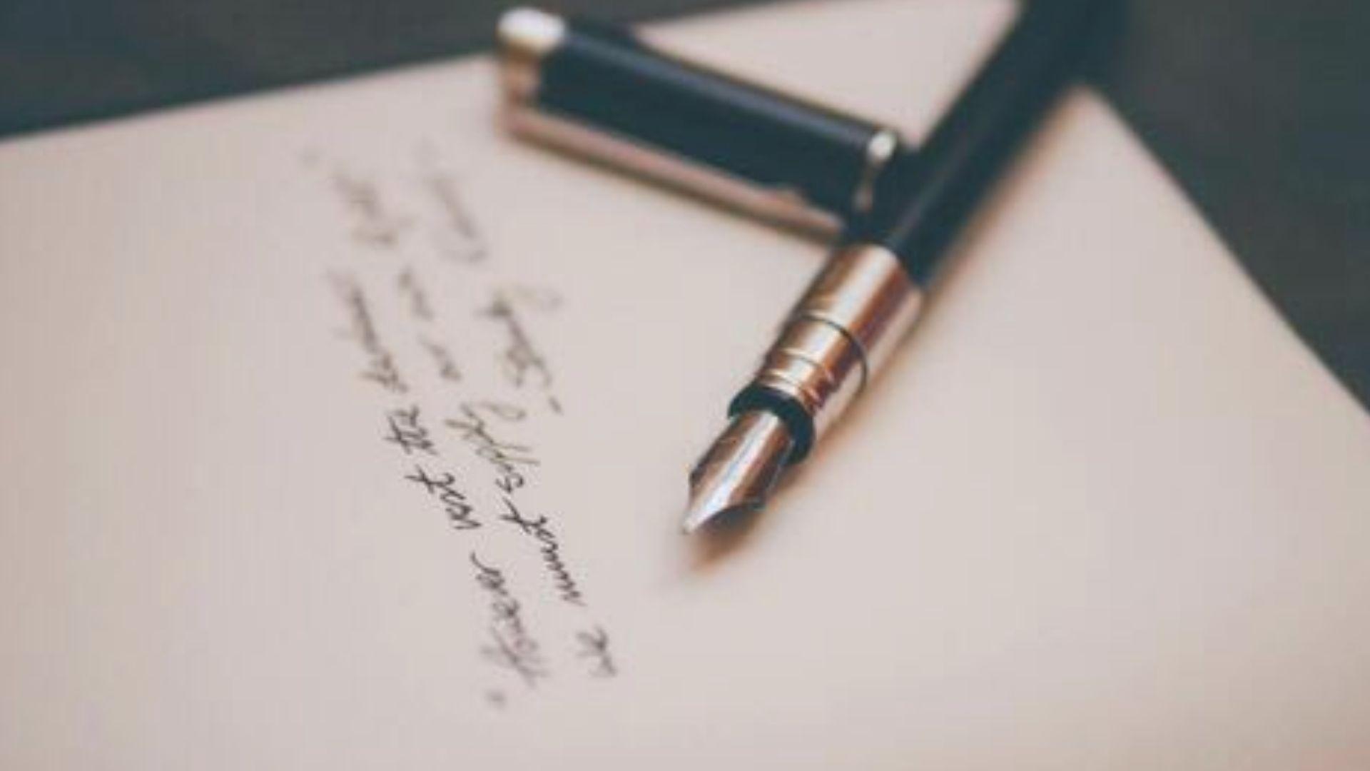 Close-up of a fountain pen resting on handwritten cursive paper