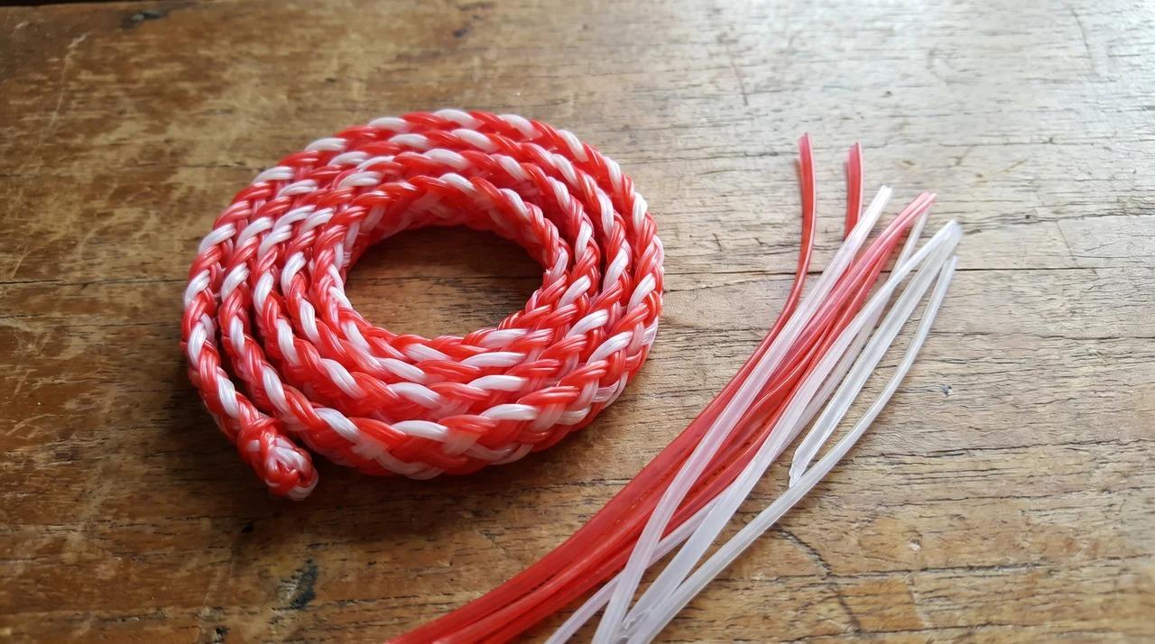 Braided red and white lanyard displayed on a wooden tabletop.