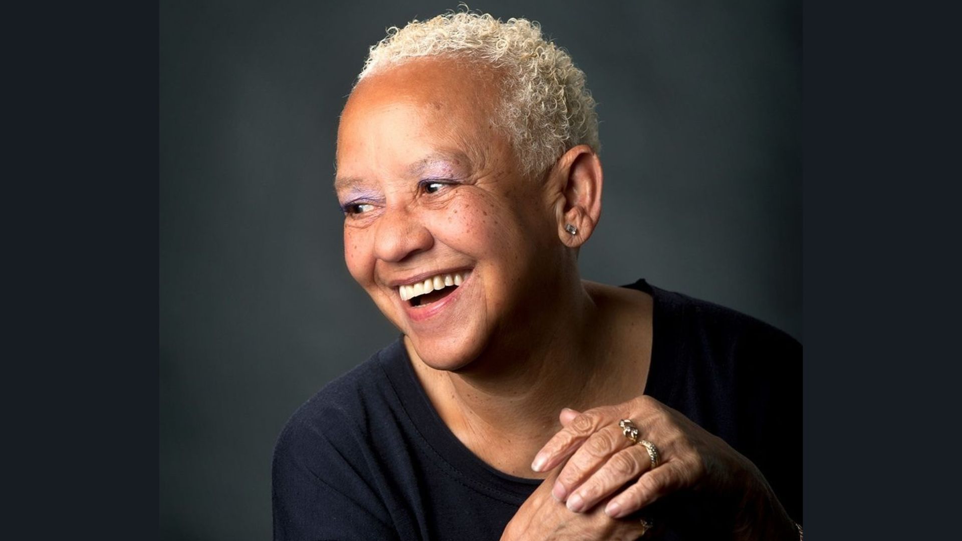 Close-up portrait of poet Nikki Giovanni smiling with short blonde curly hair