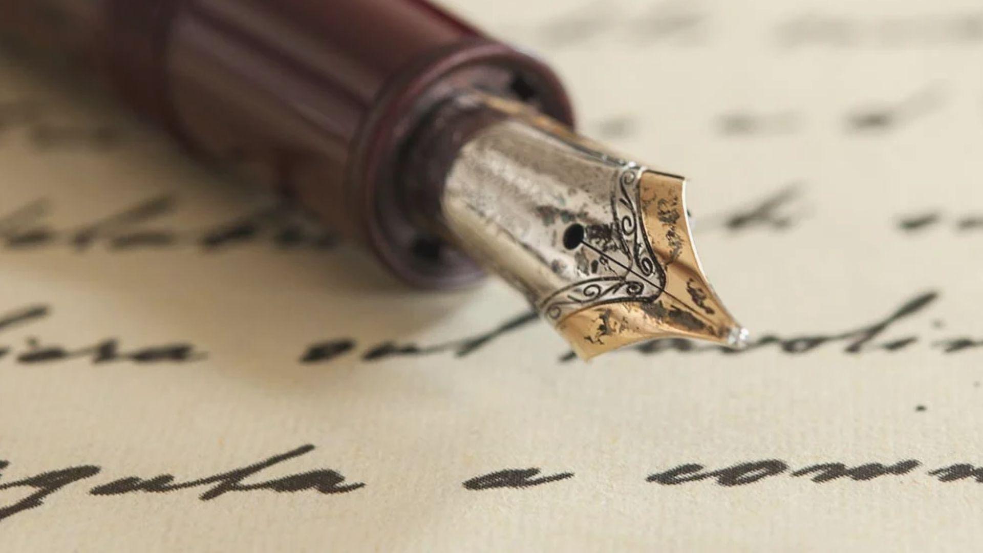Extreme close-up of ornate gold fountain pen nib on cursive handwriting