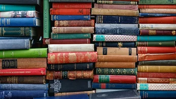 Stack of colorful vintage hardcover books piled on top of each other"