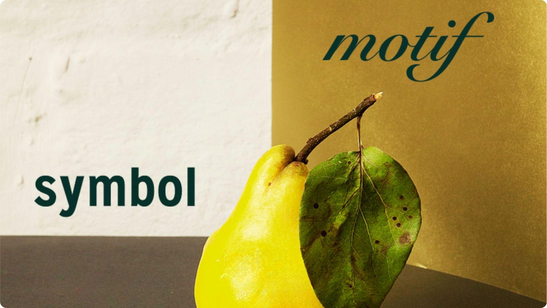 Yellow pear with leaf on table with bold text symbol and cursive motif text.File name:motif-vs-symbol