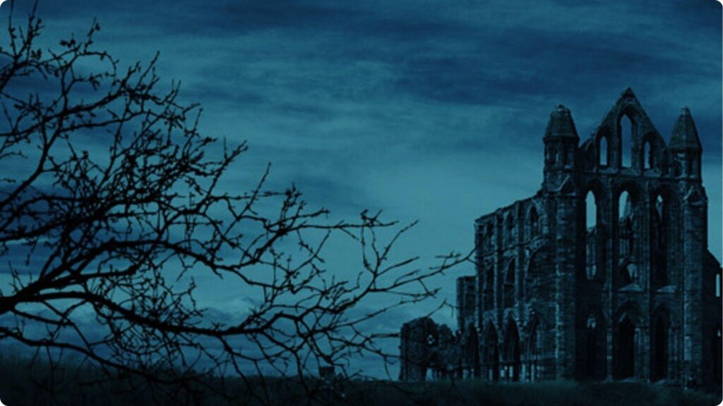 Dark gothic abbey ruin at night with bare tree branches silhouette.File Name:what-is-gothic-literature
