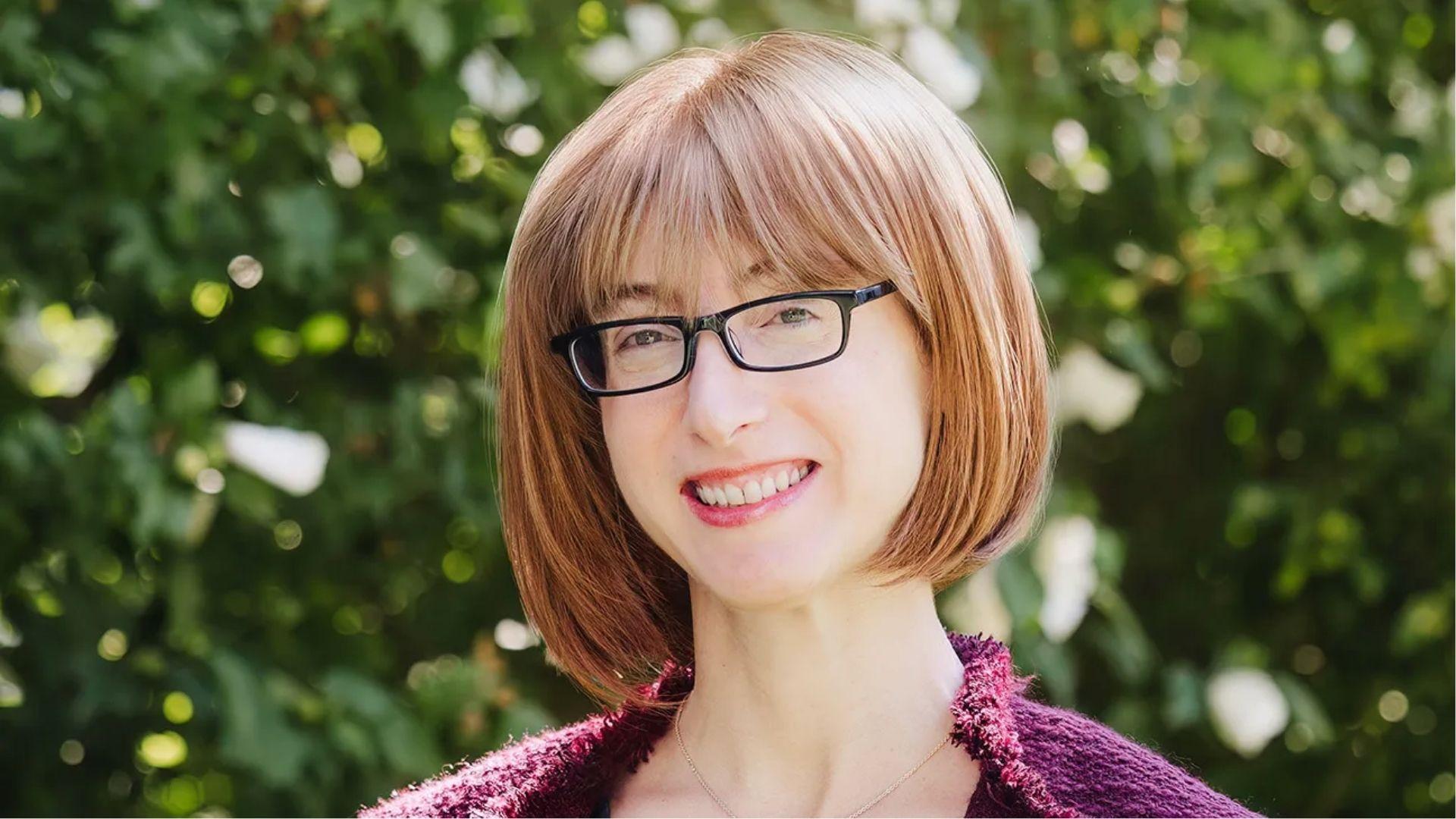 Freida McFadden smiling outdoors while wearing glasses