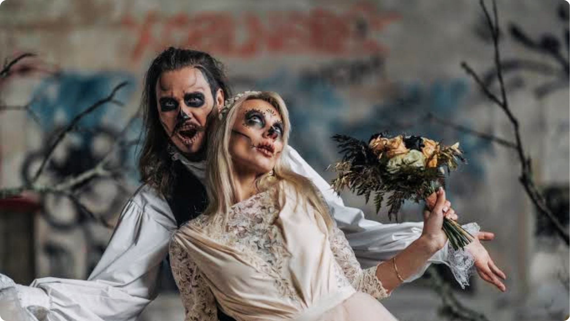 Man and woman in scary skeleton zombie makeup as creepy bride and groom.