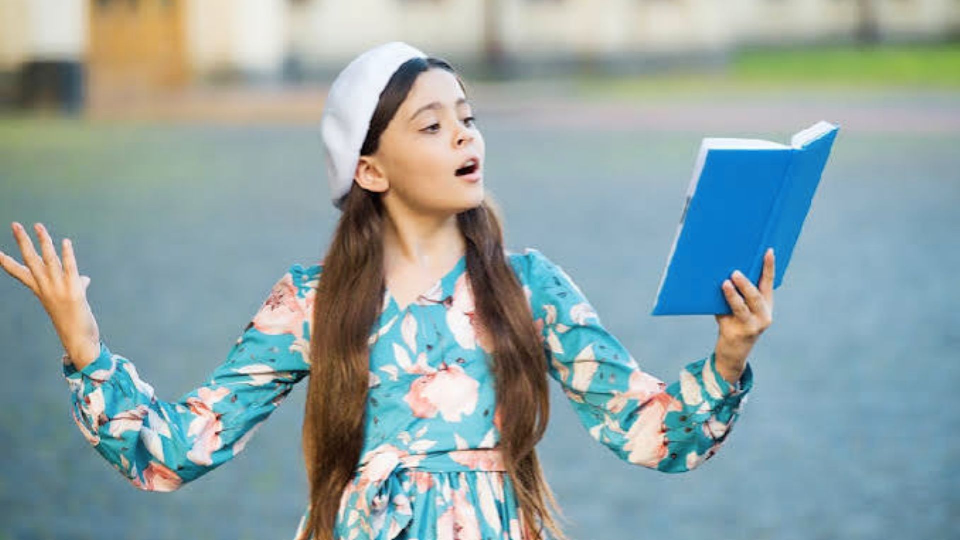 Young girl expressively reciting onomatopoeia poem from blue book.