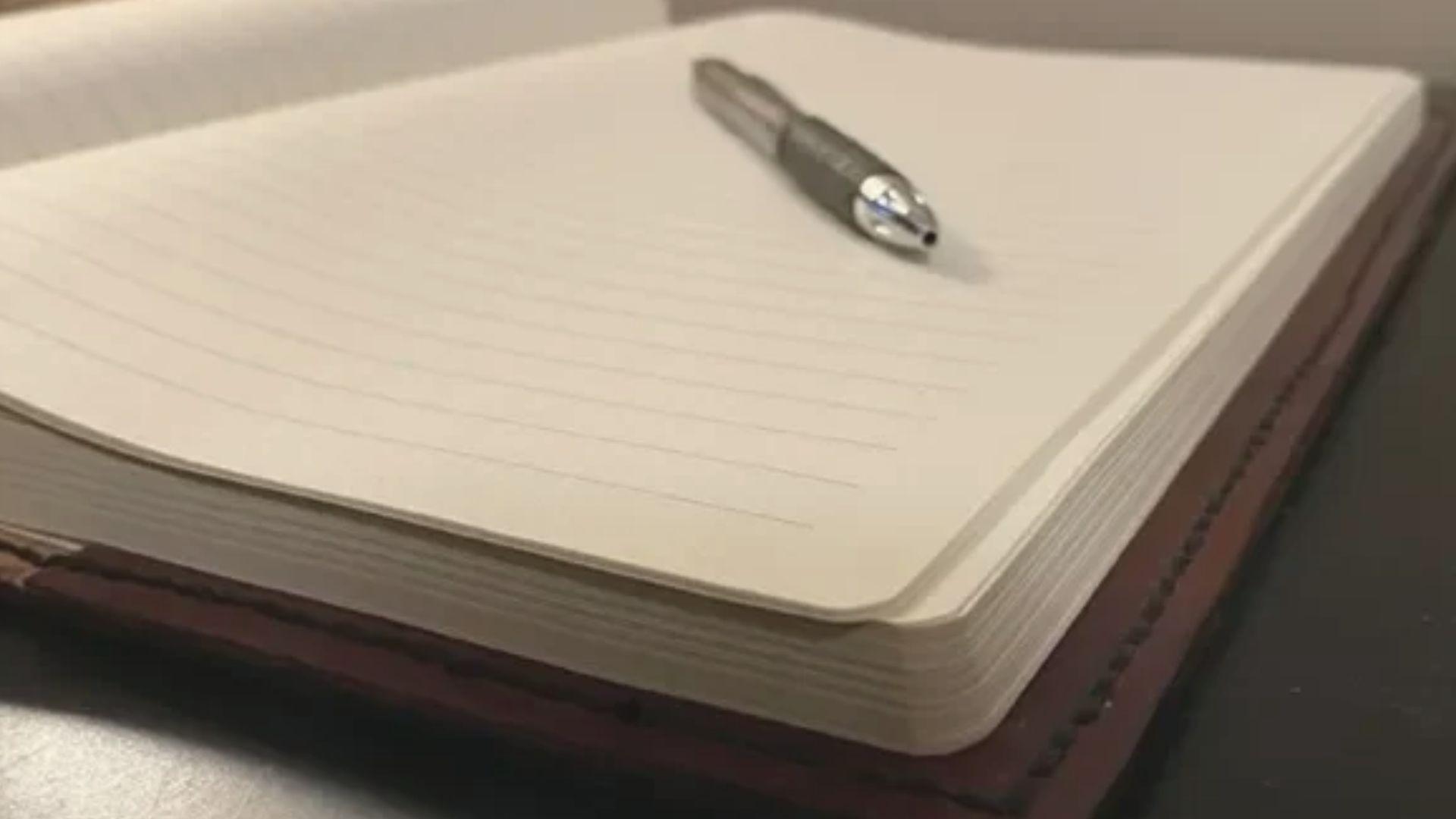 Open blank notebook with a silver pen resting on top