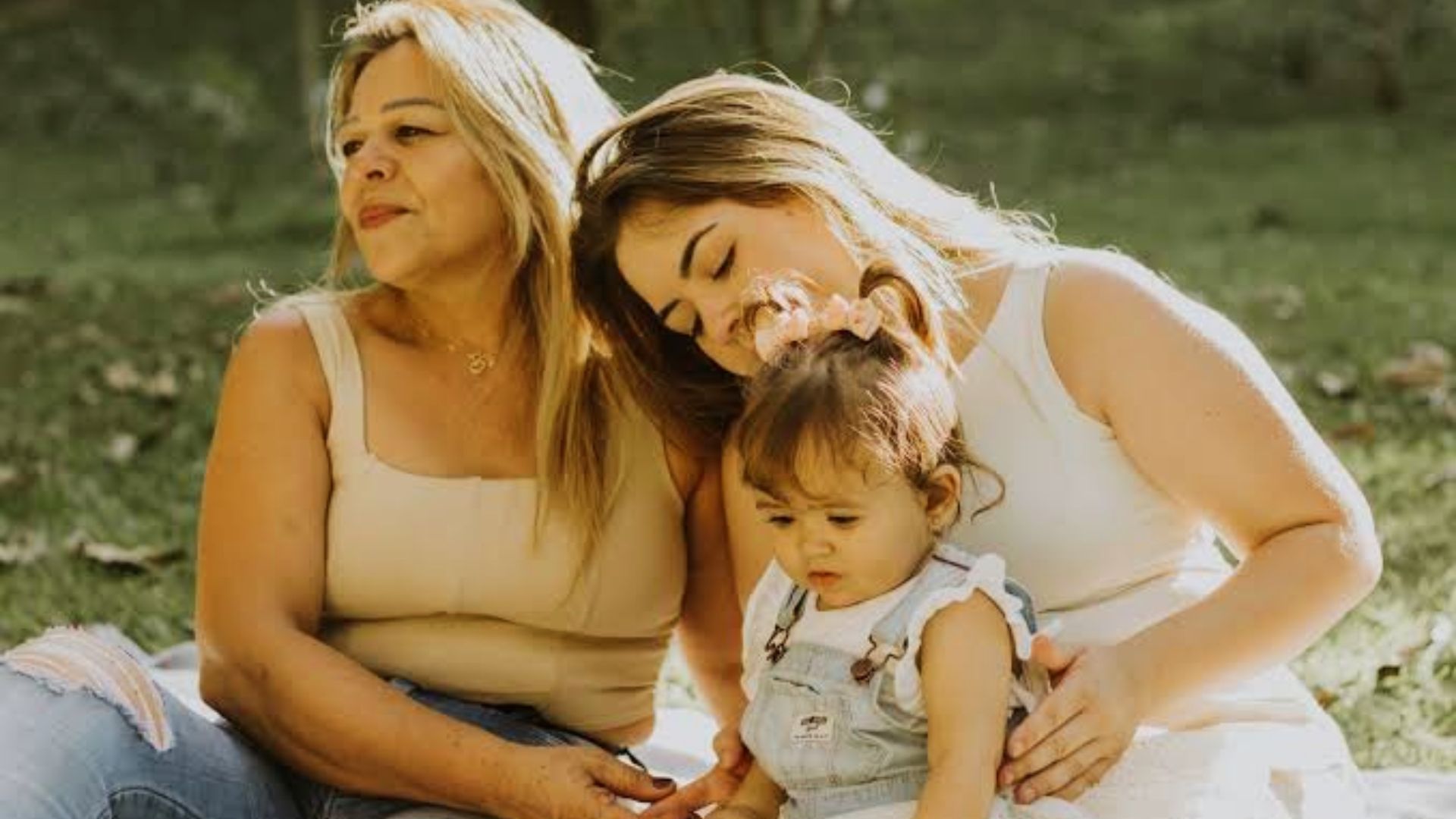 Two women sitting outdoors with a young child.