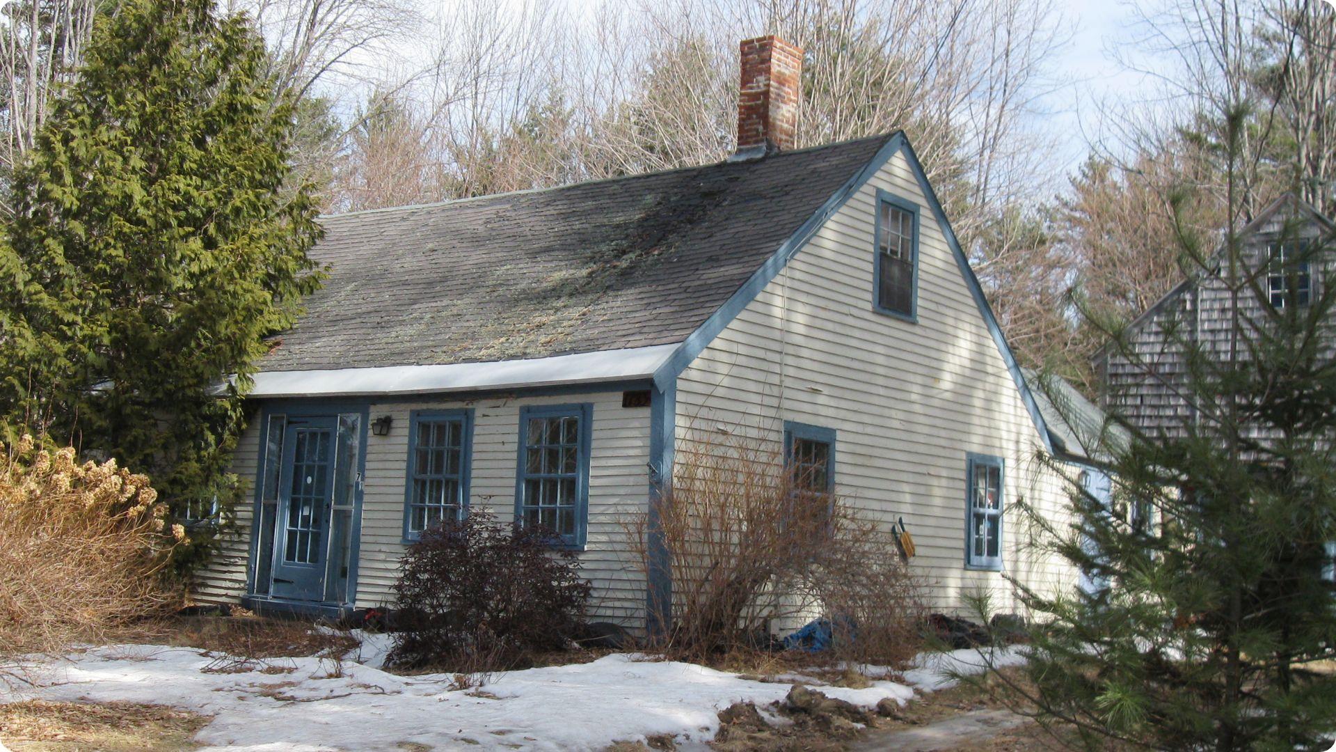 White house with blue trim and brick chimney in winter.